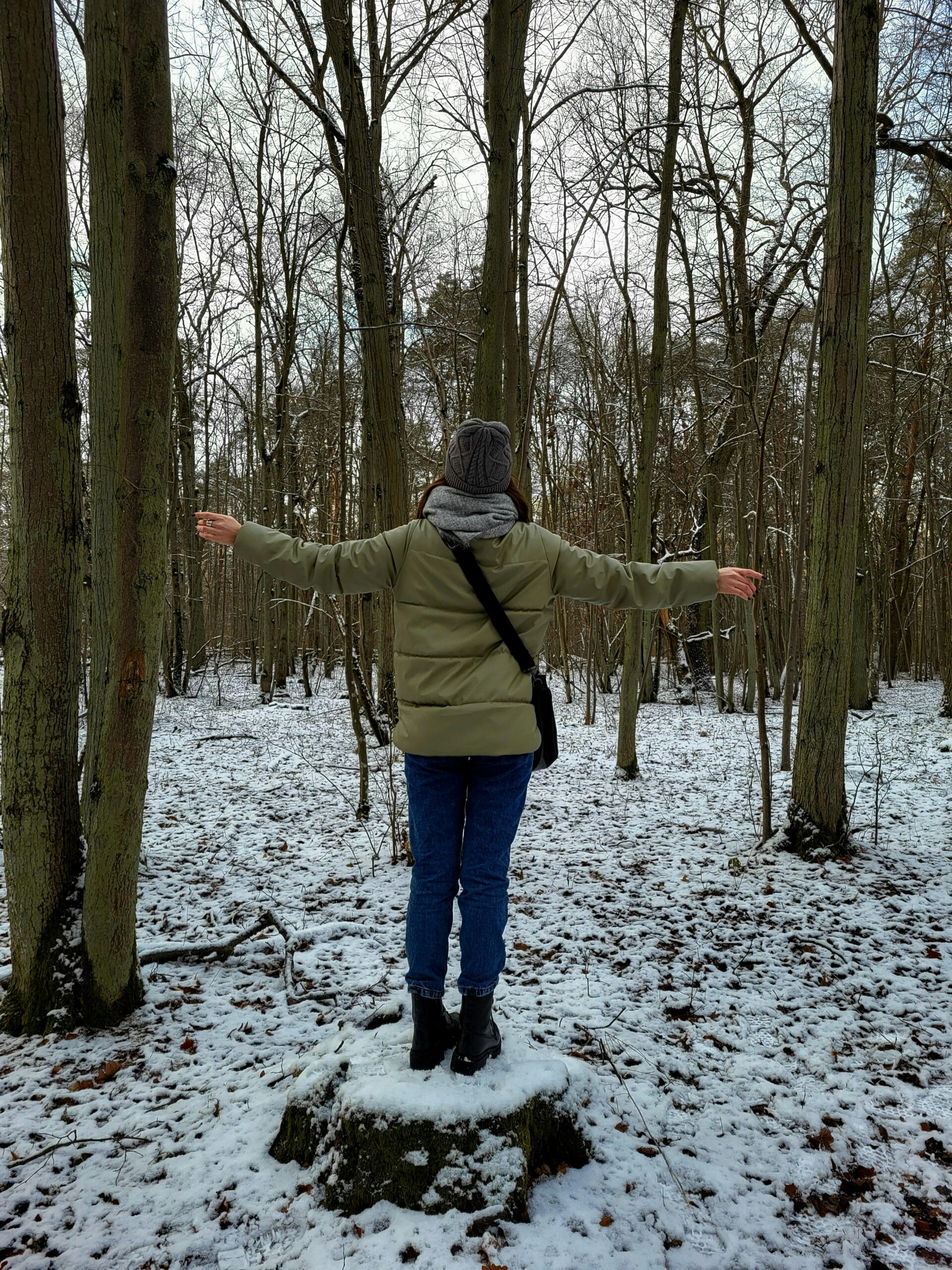 a woman standing in the woods with her arms outstretched